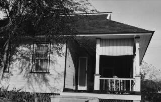 A house with an extensive balcony with view over lush woodland. House is built in a colonial style. Photographer is standing closer to the housethan in the preceding photo.