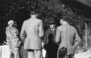 David Lloyd George in conversation with two younger men, their backs to the camera.