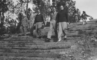 David and Gwilym Lloyd George walking down a series of wooden steps along with three others. Behind them are their caddies.