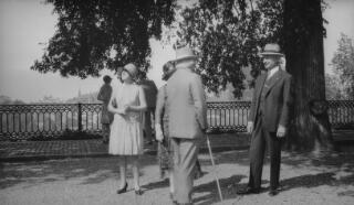David and Margaret Lloyd George in conversation with their chauffeur Dyer, possibly in gardens at Lausanne.