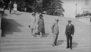 David Lloyd George in conversation with his chauffeur Dyer on the steps near Chateau Sainte Maire, Lausanne. Margaret Lloyd George and Mrs Sylvester are walking down the steps behind them.