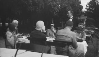 David Lloyd George and party seated at an al fresco dining table, a waiter in attendance.