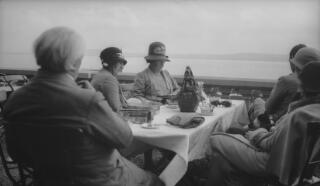 David Lloyd George and party siiting at a dining table, a lake in the background.