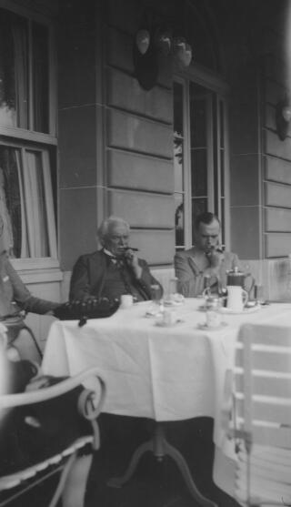 David & Gwilym Lloyd George on a hotel terrace, sitting and smoking cigars.