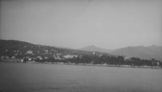 A scattered coastal settlement, hills and a distincyive mountain peak as seen from 'Sabrina' on a clear day.