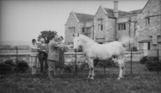 A JSylvester, another man and two women admiring a horse. In the background is a large country house. PZ7890/143, 145-146 are variants of this.