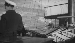 Lloyd George in greatcoat and white peaked cap on the deck of 'Sabrina.'