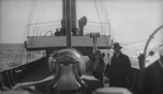 Looking from the bows along the vessel to the bridge. The ships bell is in the foreground but out of focus.