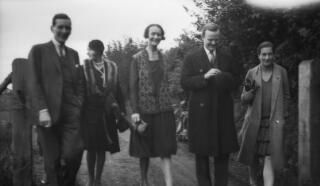 Three ladies and two men walking along a track.