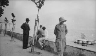 Group standing or sitting near the low wall featured in PZ7890/36. In the water is a diving platform with 'Vittoria' painted in large letters.