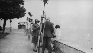 Mrs Sylvester, David, Megan & Gwilym Lloyd George on a lakeside path bounded by a low wall. D Ll G has his back to the camera.