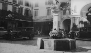 Place St Sebastien with the memorial to the aviator Chavez in the foreground. Centre left of the photo the Lloyd George entourage can be seen at a restaurant table outside the Grand Hotel Couronnes et Poste. Their cars are parked nearby.