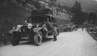 Three cars including D Ll G's Rolls Royce parked on the side of an unpaved road. Two young girls are offering flowers, one to DLlG and the other to Inspector Pavey. This may be the incident referred to by Sylvester on p185 of 'The Real Lloyd George' ...while enjoying a picnic tea peasant children presented us with bunches of Edelweiss. L.G. was thrilled and insisted on speaking to the children and giving each a present of money."