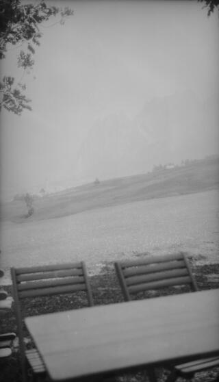 An alpine village in the distance, table and chairs in the foreground.