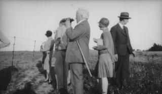 David, Megan & Gwilym Lloyd George with others inspecting a battlefield. Inspector Pavey is accompanying them. D Ll G is holding a pair of binoculars.