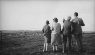 Members of the Lloyd George family, their backs to the camera, view a distant village from behind a barbed wire fence. They are (l-r) Megan, Margaret, David, Gwilym Lloyd George.