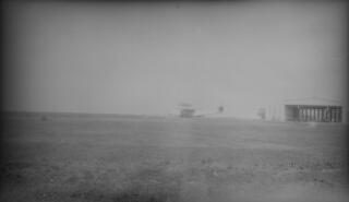 An aeroplane on the ground at an unknown aerodrome. The plane is seen from a distance but is very similar to a Dornier Do-X seaplane.The Do-X was financed by the German Transport Ministry and built in a specially designed plant at Altenrhein,on the Swiss portion of Lake Constance, in order to circumvent the Treaty of Versailles which forbade any aircraft exceeding set speed and range limits to be built in Germany after World War I. The plane was completed in 1929. In his diary A J Sylvester writes that the Lloyd George entourage witnessed it taking off on a trial flight on Sept 4th 1929.