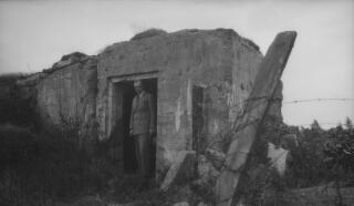 Gwilym Lloyd George standing in the doorway a concrete pillbox. On page 187 of 'The Real Lloyd George' A J Sylvester writes "We motored rapidly through Belgium and passed over the battlefields again,this time visiting dug-outs which Gwilym had occupied during the war..." This may be one such dug-out.