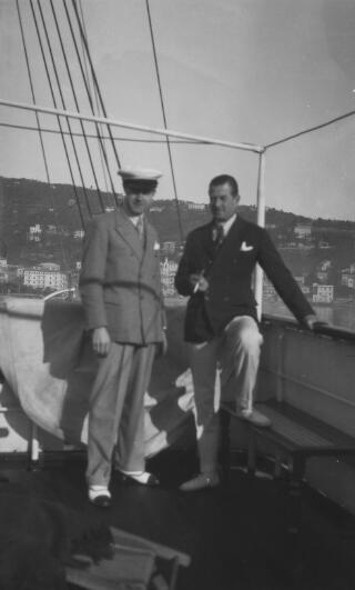 A J Sylvester(left) and Sir Thomas Carey Evans on the deck of 'Sabrina.' The yacht appears to be anchored in Santa Margherita Ligure. The foreground, including the two sitters, is out of focus.