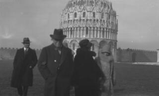 David and Margaret Lloyd George, Inspector Pavey and others in front of the Baptistry, Piazza dei Miracoli, Pisa. The entourage are out of focus but the Piazza in the background is in focus.
