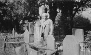 David Lloyd George standing amogst headstones in an unidentified cemetery or churchyard.