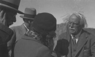 A windswept David Lloyd George in conversation with his daughter Megan whilst others look on.